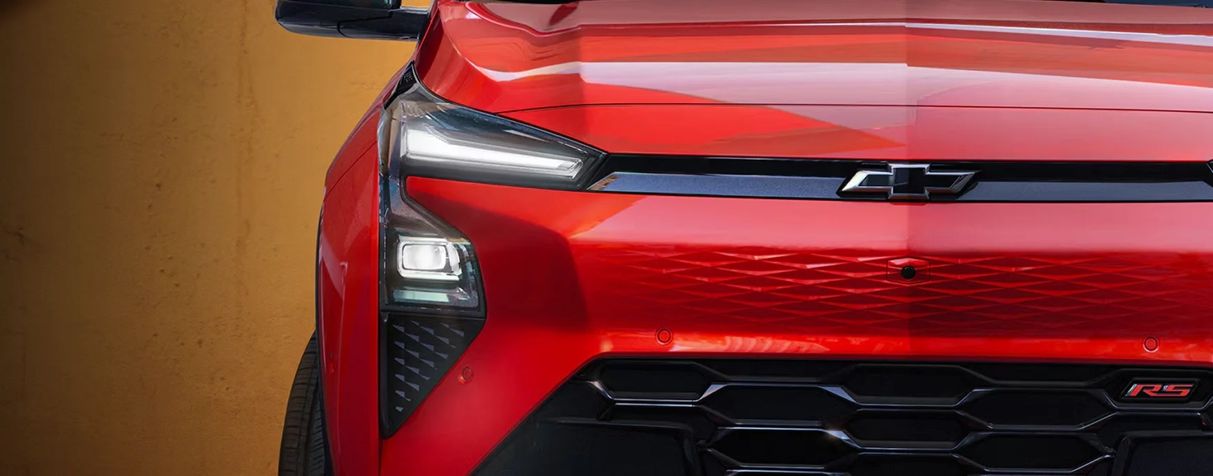 2027 Chevrolet Bolt RS driving on a city street at dusk